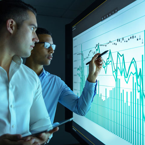 Businessmen studying graphs on an interactive screen in business meeting Businessmen studying graphs on an interactive screen in business meeting